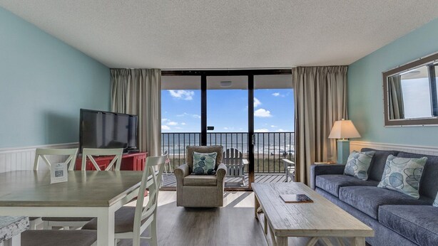 Ein Zimmer mit Balkon, Essbereich, Sofa und Fernseher.