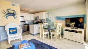 A compact living space with a kitchen, dining area, and a TV. - 0910 Gone To The Beach by Atlantic Towers (Carolina Beach)