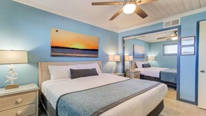 A bedroom with a bed, bedside tables, a ceiling fan, and a painting of a sunset. - 0910 Gone To The Beach by Atlantic Towers (Carolina Beach)