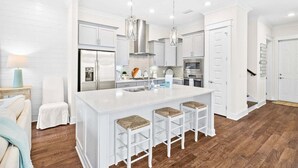 A modern kitchen with white cabinetry, a large island with bar stools, stainless steel appliances, and pendant lighting. - ✨ Modern 30A Stay | Golf Cart | Pool Access (Inlet Beach)