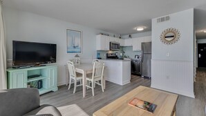 A modern kitchen with white cabinets, a stainless steel refrigerator, and a microwave. - 0609 Oceanfront Escape by Atlantic Towers (Carolina Beach)