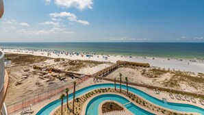 A beach resort with a swimming pool, beach umbrellas, and a sandy shoreline. - Phoenix Gulf Towers 402 2 Bedroom Condo (Orange Beach)