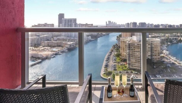 A balcony with a view of a river and cityscape, featuring two bottles of champagne and a tray.