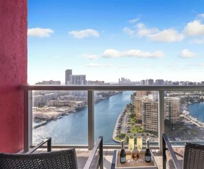 Un balcón con vistas a un río, edificios y un puerto deportivo.