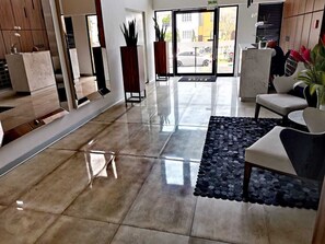 Experience the sleek lobby with a polished floor, reception desk, and comfortable seating area.