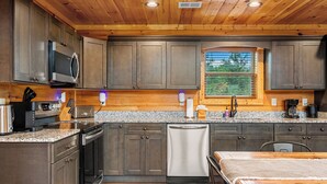 Una cocina moderna con encimeras de granito, electrodomésticos de acero inoxidable y armarios de madera.