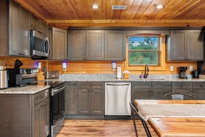 Eine moderne Küche mit Granitarbeitsplatten, Edelstahlgeräten und Holzausbau.