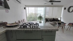 A modern kitchen with a gas stove, a ceiling fan, and a large window overlooking a balcony.