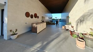 A spacious lobby with a reception desk, potted plants, and a view of the outdoors.