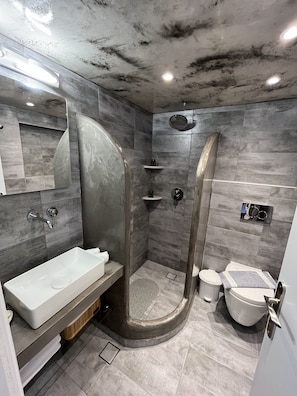 Un baño moderno con cabina de ducha curva, un lavabo blanco y un inodoro.