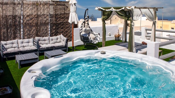 Jacuzzi con vistas al mar, mobiliario exterior y una pérgola.