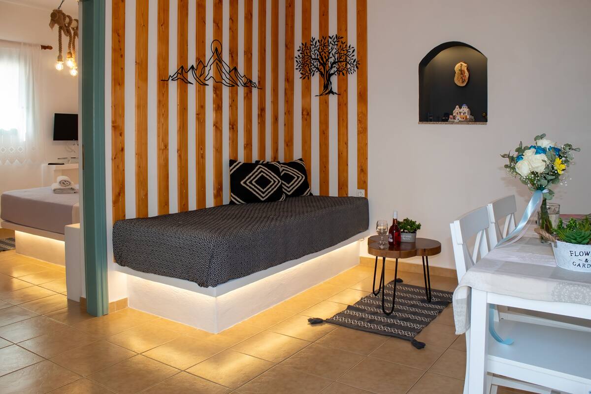Une chambre à coucher moderne avec un lit, une petite table sur laquelle est posé un vase, et un téléviseur fixé au mur.