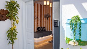 Una habitación con cama, una lámpara de pared y una puerta que da a otra estancia.