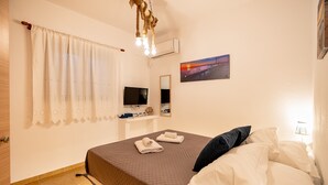 Una cama hecha con cuidado, con un edredón marrón, almohadas blancas y una toalla doblada sobre una pared blanca.