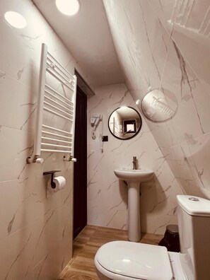 Ein kleines Badezimmer mit Toilette, Waschbecken und Spiegel.