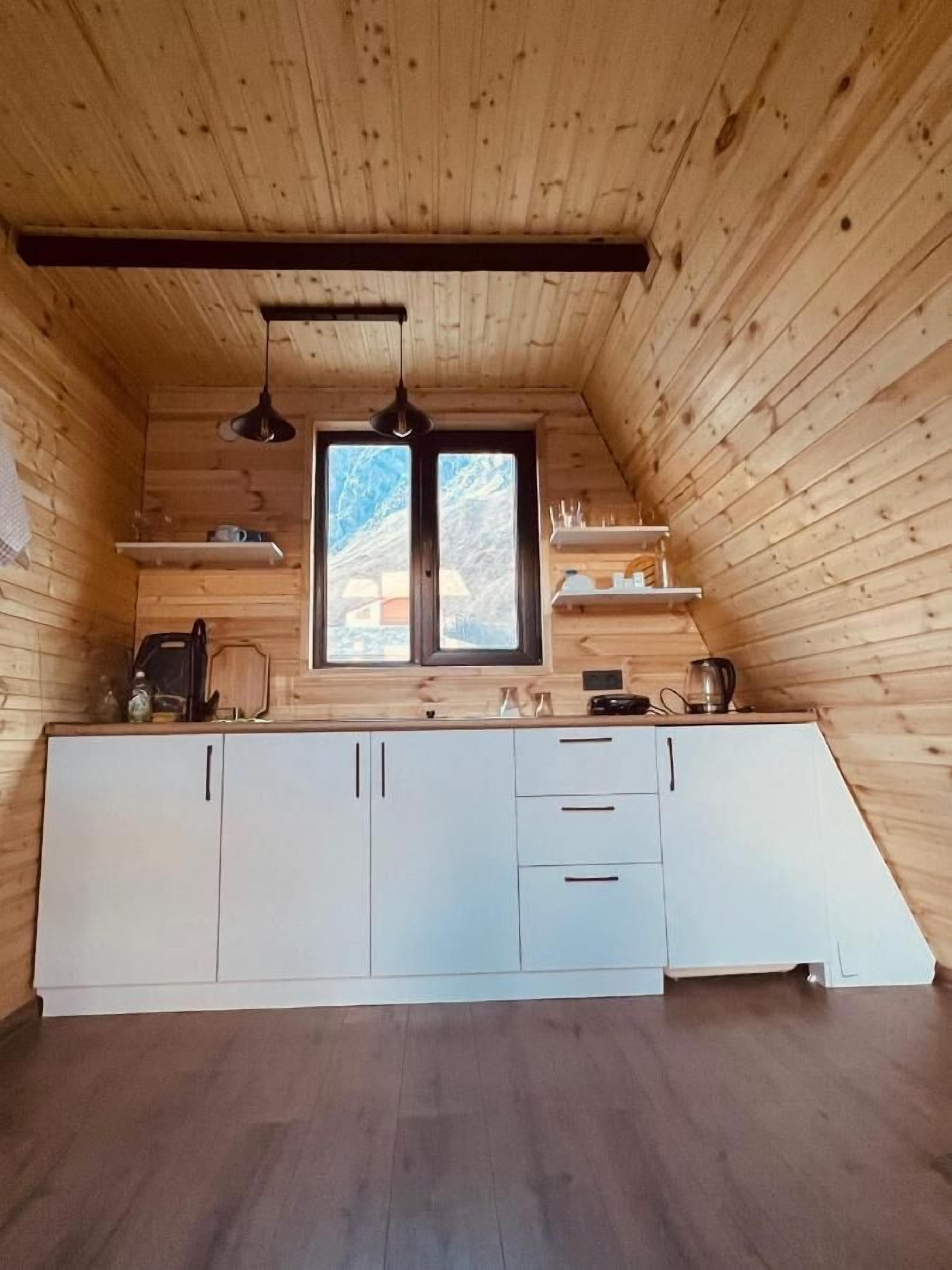 Een kleine keuken met houten wanden, een raam en een schuin dak.