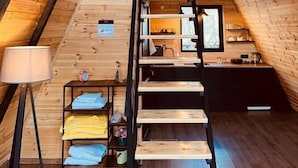 A cozy attic bedroom with a sloped ceiling, a wooden ladder, a bed, a desk, and a window. - PYRAMID KAZBEGI (Kazbegi)