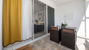 Ein Zimmer mit einer Schiebetür, einem kleinen Tisch mit Stühlen und einem Blumentopf.