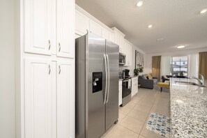 Enjoy meals in the well-equipped kitchen with stainless steel appliances, white cabinetry, and a granite countertop.