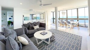 A modern living room with a grey sofa, a round coffee table, and a view of the ocean through large windows. - Absolute Beachfront Bliss on Kings Beach (Kings Beach)