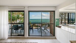 A modern kitchen with a view of the ocean, a dining area with chairs, and a large sliding glass door. - Absolute Beachfront Bliss on Kings Beach (Kings Beach)