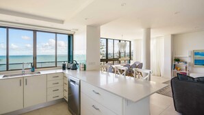 A modern kitchen with a large island, a dining area with a view, and a living space with a sofa and a bookshelf. - Absolute Beachfront Bliss on Kings Beach (Kings Beach)
