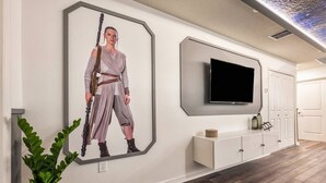 A hallway with a framed artwork, a television mounted on the wall, a potted plant, and a wooden floor. - Last Minute Disney Getaway! Townhouse with Private Pool. Book Now! #66503 (Orlando)