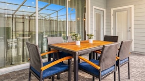 A patio with a wooden table and wicker chairs, large glass windows, and a door. - Last Minute Disney Getaway! Townhouse with Private Pool. Book Now! #66503 (Orlando)