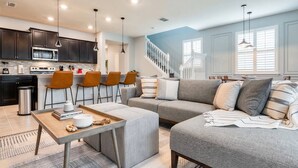 A modern kitchen with dark cabinets, a microwave, and a dining area with a table and chairs. - Last Minute Disney Getaway! Townhouse with Private Pool. Book Now! #66503 (Orlando)