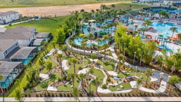 A resort with a large pool, palm trees, and a winding pathway.