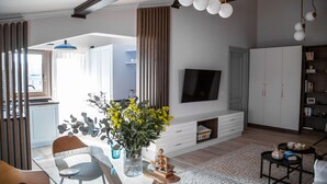 A modern living room with a TV, wooden furniture, and a decorative vase.