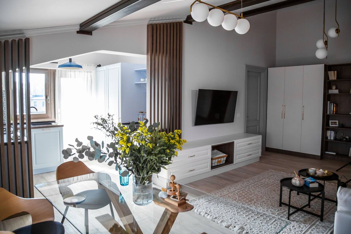 A modern living room with a TV, wooden furniture, and a decorative vase.