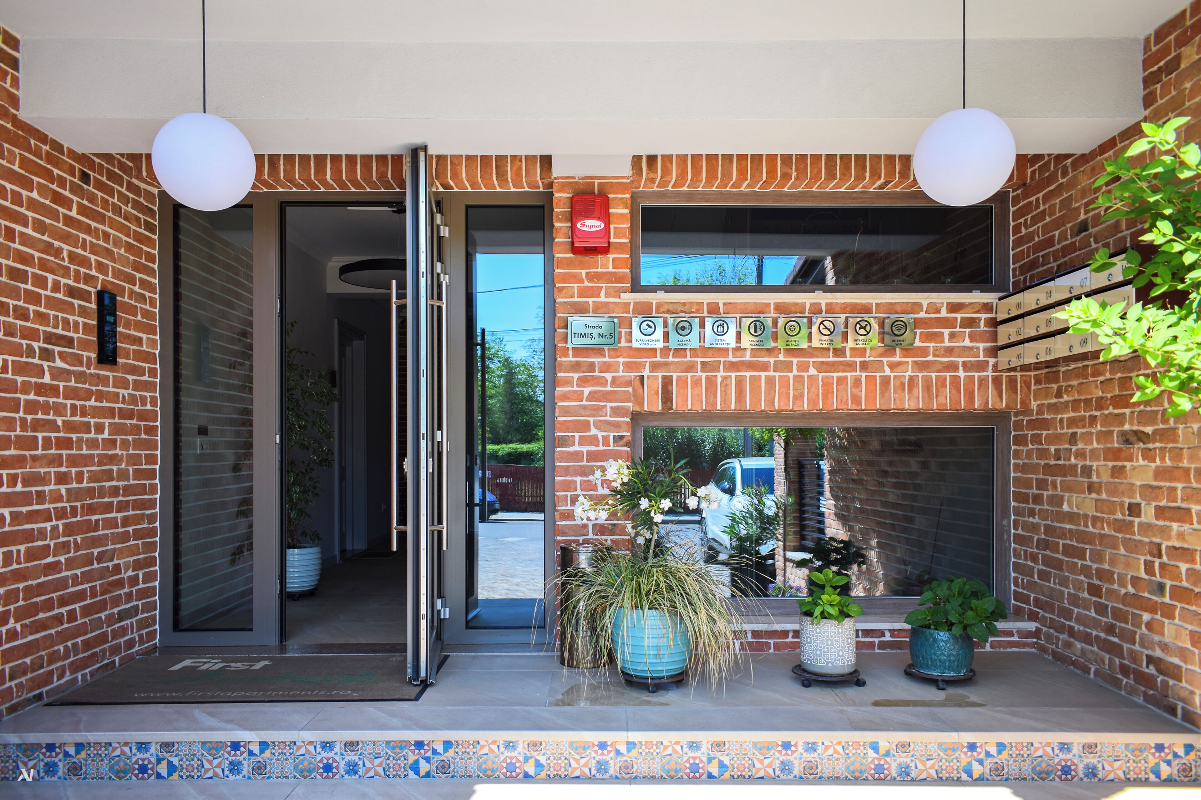 A hotel entrance with a brick facade, a glass door, and potted plants.
