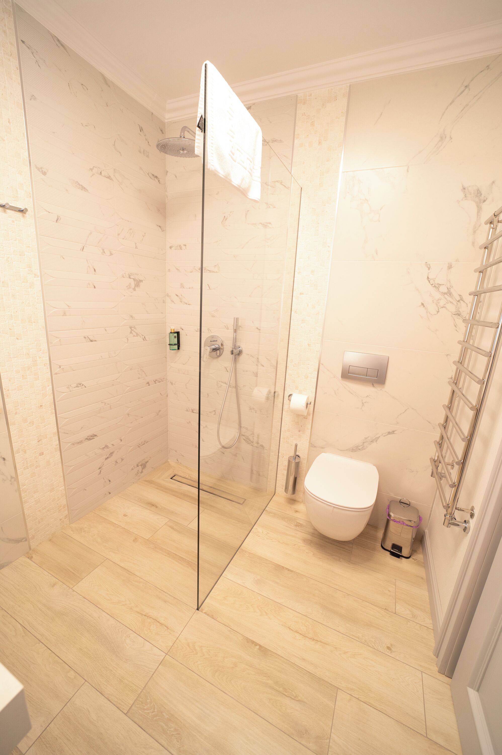 A modern bathroom with a glass-enclosed shower, a toilet, and a towel rack.
