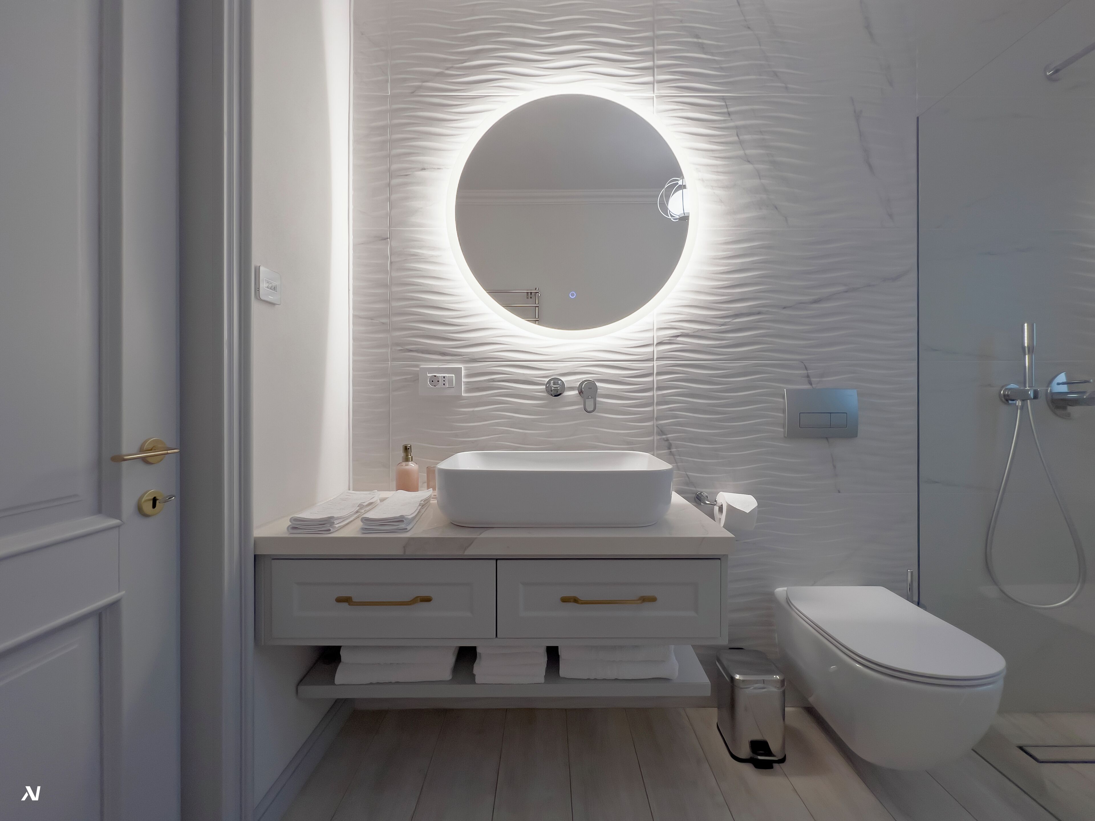 Un baño moderno con un espejo redondo, un lavabo blanco y un inodoro.