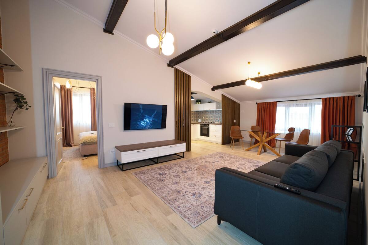 A modern living room with a sofa, TV, and dining area.