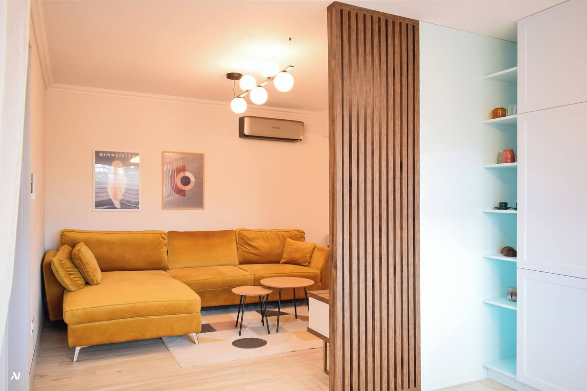 A modern living room with a mustard-colored sofa, a small round table, and a built-in white cabinet.