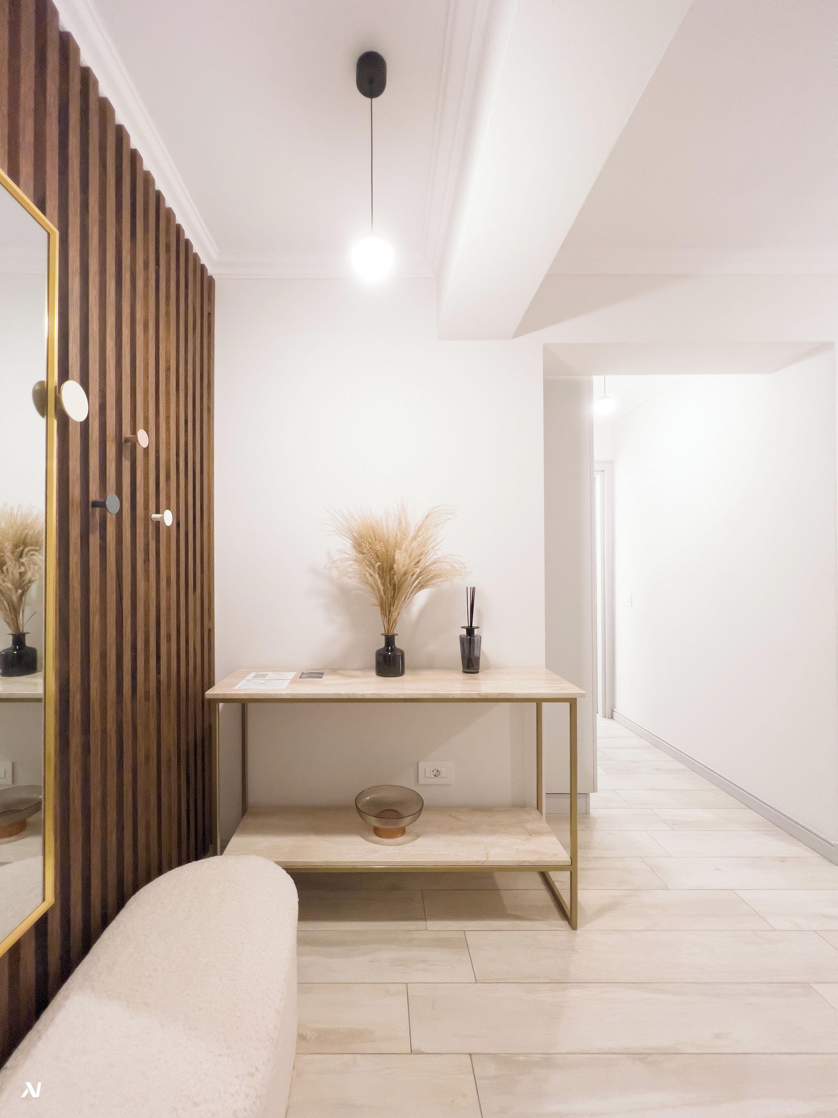 A modern, minimalist room with a wooden slat wall, a white console table with a vase and a bowl, and a large mirror.