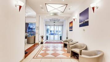 Hall d'albergo con reception, area relax e vista sulla strada attraverso le vetrate.