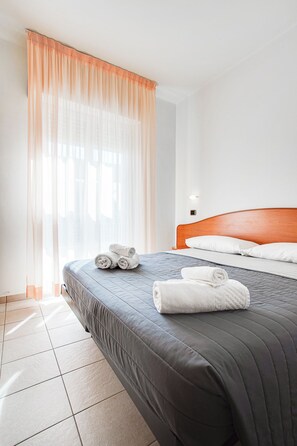 Una habitación de hotel con cama, almohadas y toallas enrolladas.