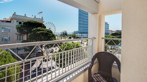 A balcony with a view of a Ferris wheel, a building with a clock tower, and a modern high-rise building. - Villa Maria (Cesenatico)