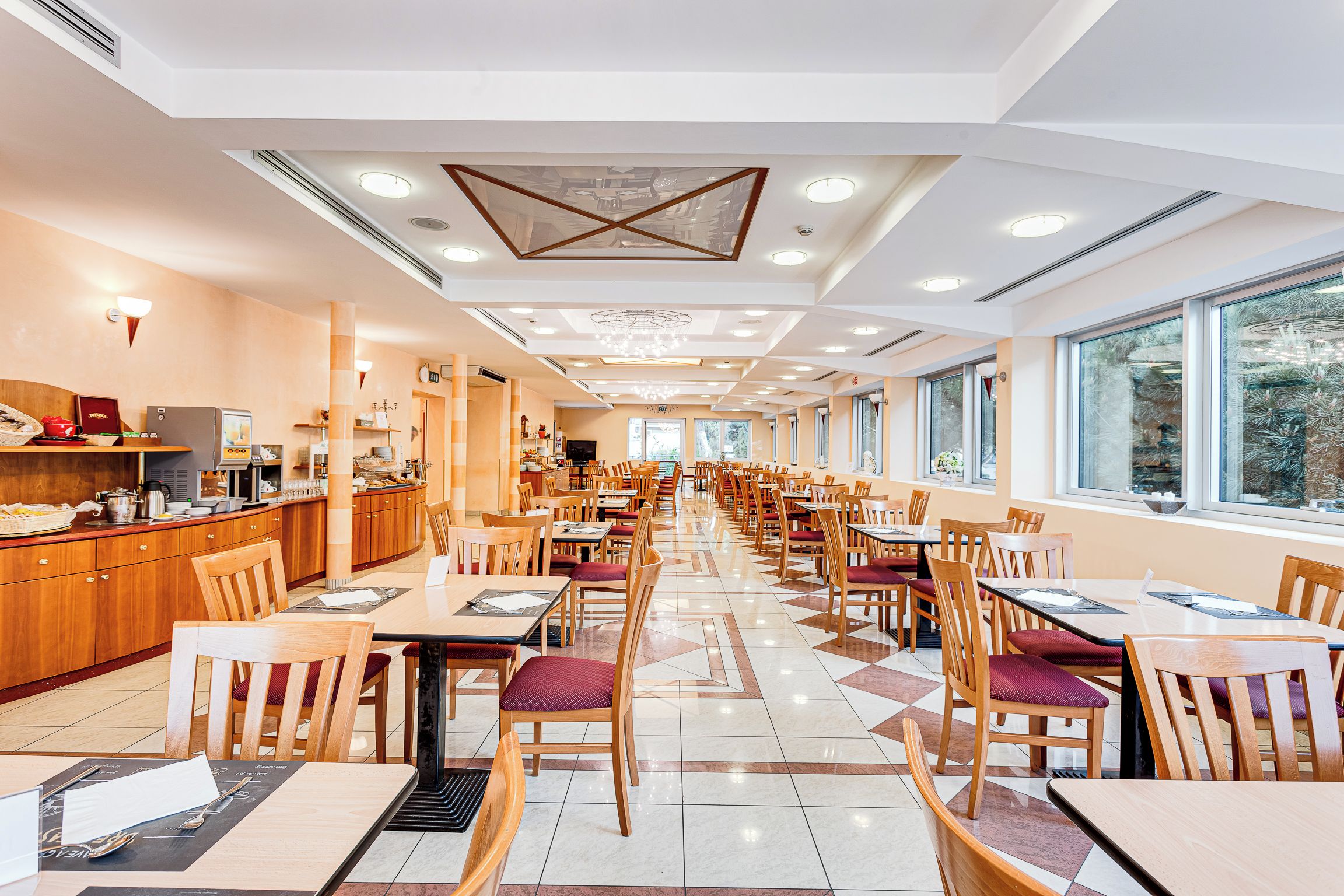 A spacious restaurant with a long counter, multiple tables, and chairs.