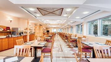 Un'ampia sala ristorante con un lungo bancone, diversi tavoli e sedie.