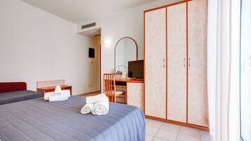 Una camera d'albergo con un letto, una scrivania, una sedia, un armadio e uno specchio.