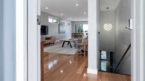 Una sala de estar moderna con piso de madera, un comedor y una escalera.