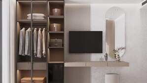 Une chambre moderne dotée d’une armoire intégrée, d’un téléviseur à écran plat fixé au mur, d’une petite coiffeuse avec un miroir et d’une poubelle.