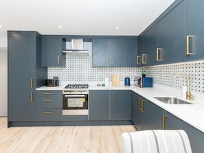 Features a sleek kitchen with gas stove, oven, and stainless steel sink.
