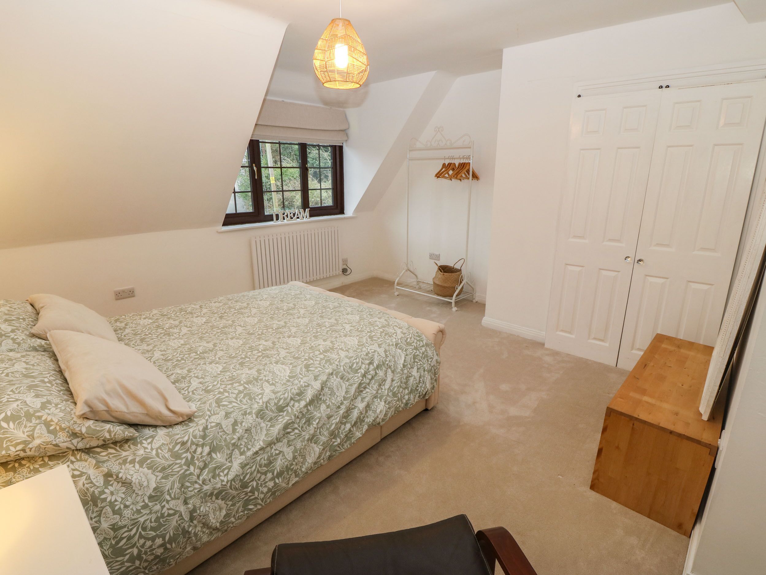 Une chambre à coucher avec un lit, une fenêtre, un radiateur, un banc en bois et une armoire.