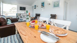 A dining area with a wooden table set for breakfast, including plates, cutlery, and glasses. - Wagtails (Dartmouth)