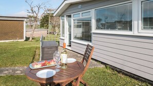 A patio with a table set for a meal, a bottle of wine, and a plate of food. - Wagtails (Dartmouth)
